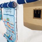 Aufrollbare Fundertable-Paneele unter dem Tisch befestigt – ein Stoffpanel mit Küchenillustration und ein Panel mit Fensteröffnung, kombiniert mit navyblauem Waffelstoff und weißen Schlaufen.