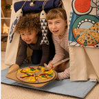 Zwei Kinder spielen in einer Fundertable Base mit Spielmatte und Funderchef-Themenklappe. Sie servieren eine selbstgebastelte Pizza aus Karton.