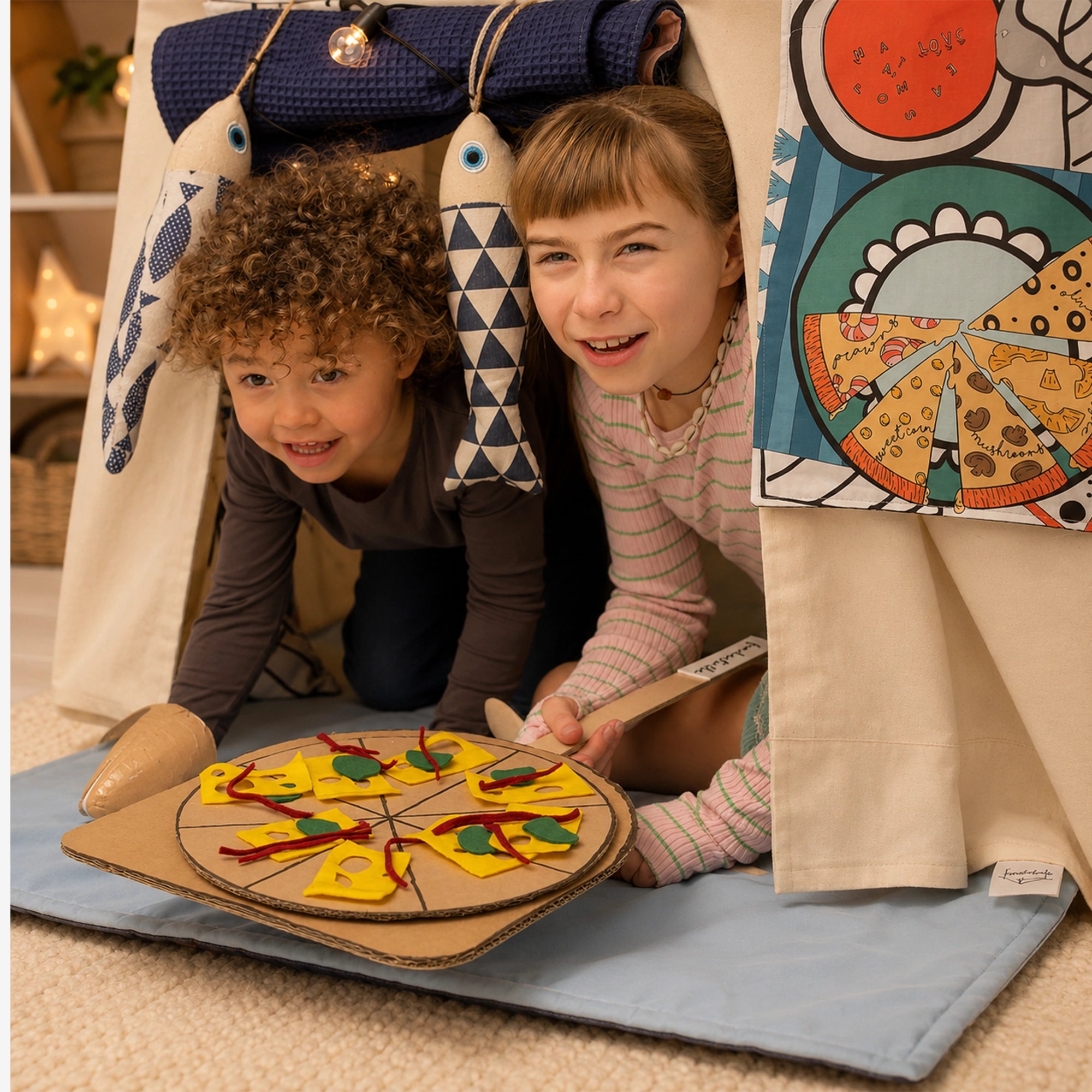 Zwei Kinder spielen in einer Fundertable Base mit Spielmatte und Funderchef-Themenklappe. Sie servieren eine selbstgebastelte Pizza aus Karton.