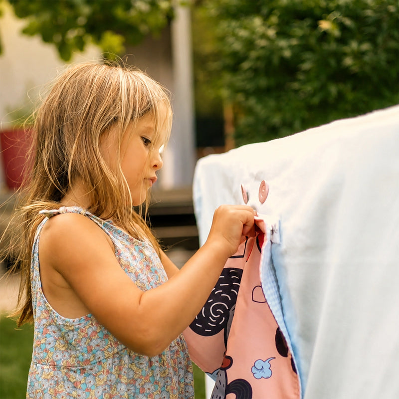 Kind wechselt ein Fundertable Fenster an der Base im Garten. Austauschbare Fenster und Türen schaffen immer neue Spielwelten unter dem Tisch und fördern kreatives, selbstbestimmtes Spielen im Familienalltag.