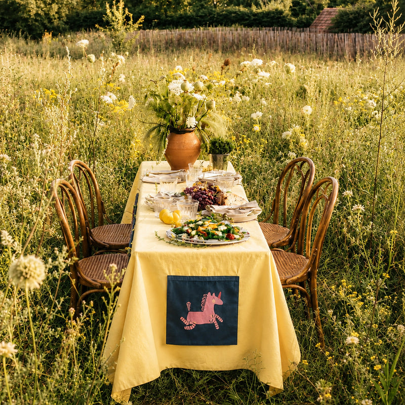 Fundertable Base mit Einhorn-Fenster auf einem Familientisch im Garten. Die textile Spielwelt unter dem Tisch schafft Raum für Fantasie, kreatives Spielen und gemeinsame Familienmomente – drinnen und draußen.