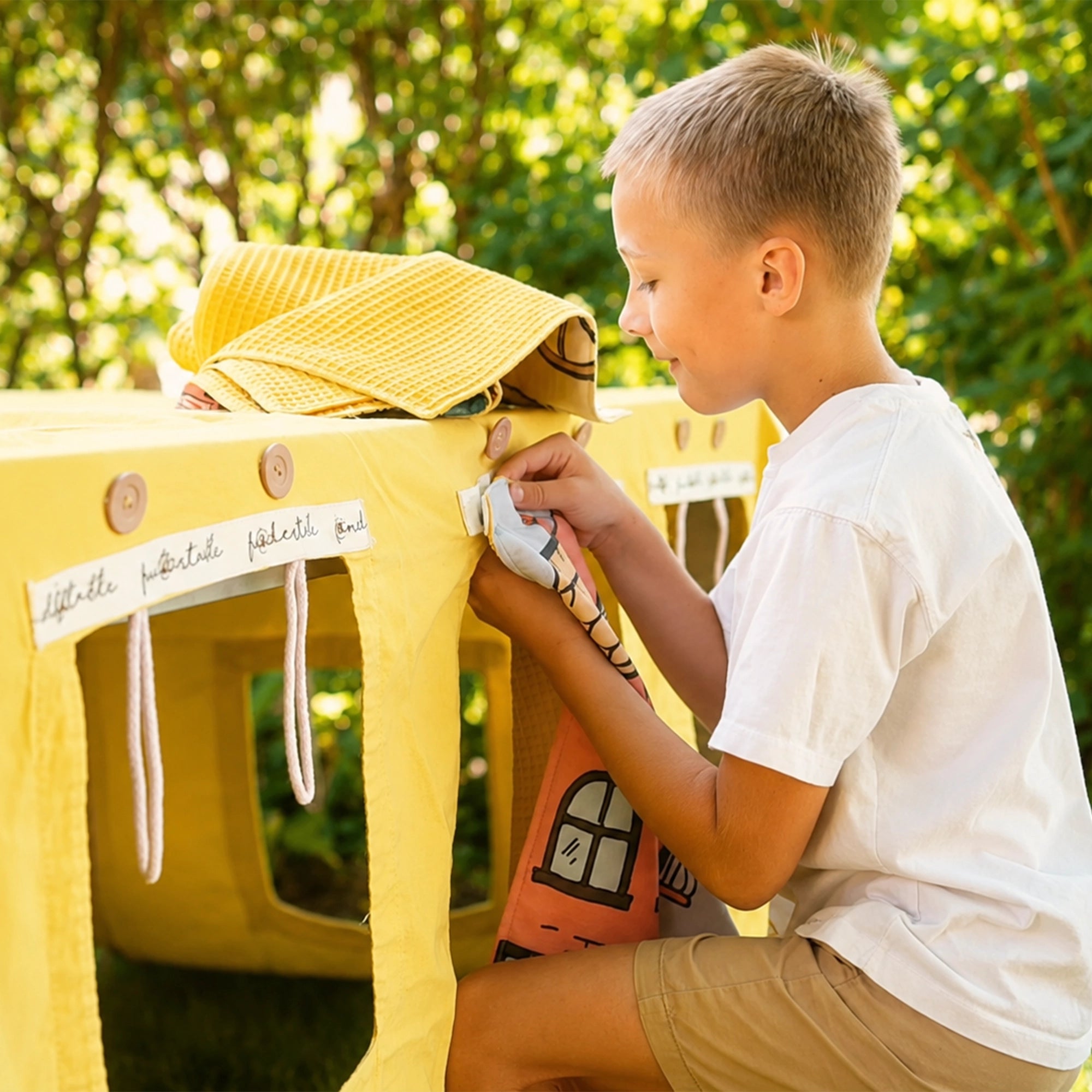 Kind befestigt ein Fundertable Fenster mit Druckknöpfen an der Base. Das modulare System mit austauschbaren Fenstern und Türen ermöglicht flexible Spielwelten und immer neue Abenteuer unter dem Tisch.