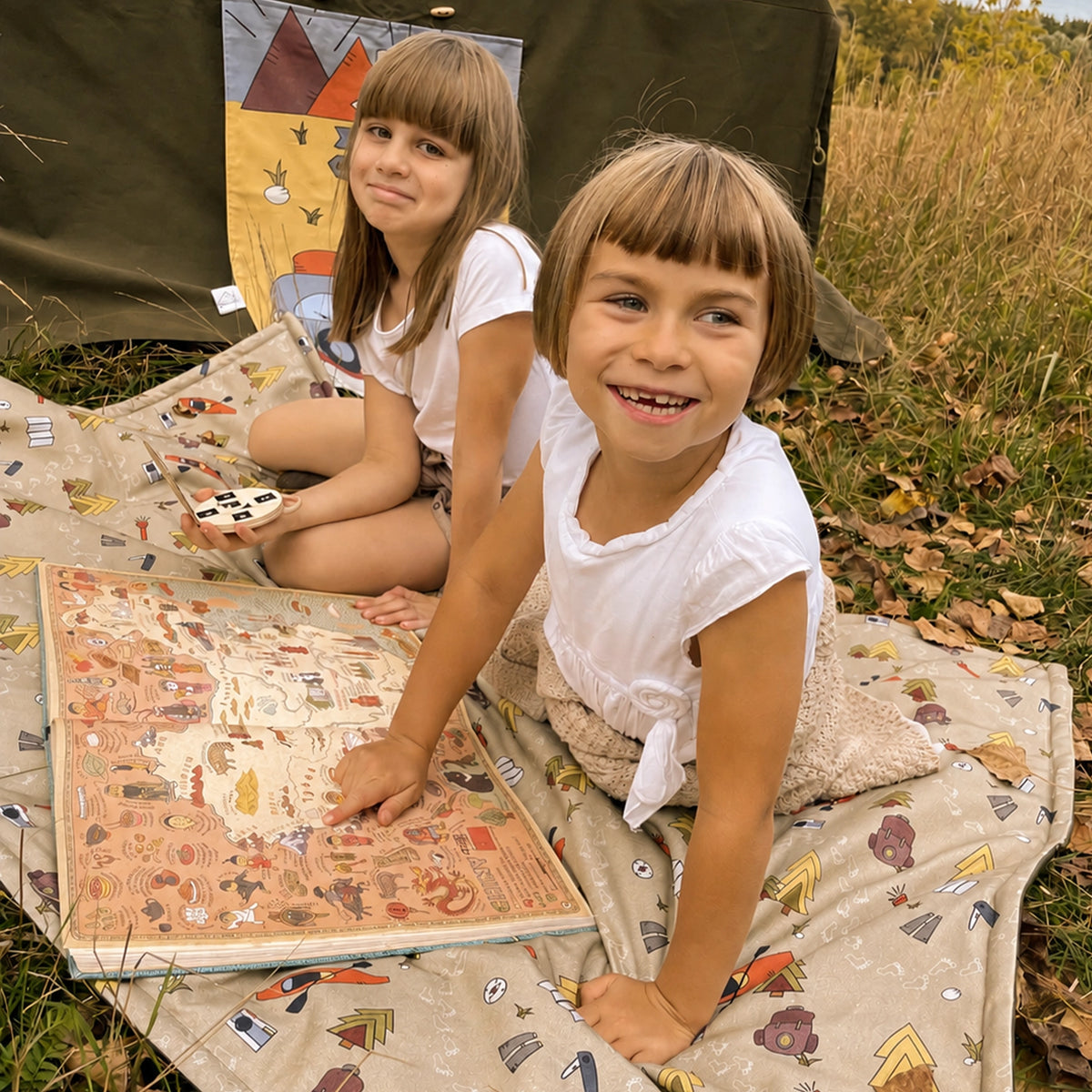 Zwei Kinder entdecken gemeinsam eine Schatzkarte auf einer Fundertable Spielmatte im Freien. Die weiche, gepolsterte Matte schafft einen gemütlichen Platz für Abenteuer, Fantasie und gemeinsames Spielen unter dem Tisch und darüber hinaus.