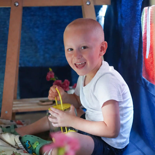 Kind sitzt in einer Fundertable Spielhöhle unter dem Tisch und spielt. Die textile Baumwoll-Base schafft einen geschützten Rückzugsort für Fantasie, Ruhe und kreatives Spielen im Familienalltag.