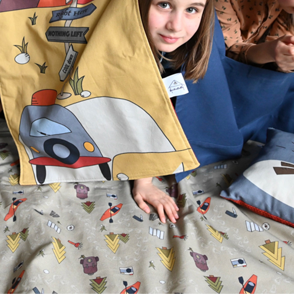 Fundertable im Camping-Design im Einsatz – ein Kind spielt unter dem Tisch auf der weichen Spielmatte und taucht in fantasievolle Abenteuer mitten im Familienalltag ein