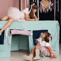 Zwei Kinder spielen mit der Fundertable Base in Cool Mint Chip und der Spielwelt City Born Unicorns. Die textile Spielhöhle unter dem Tisch lädt zu Rollenspielen, Fantasie und gemeinsamen Momenten ein.